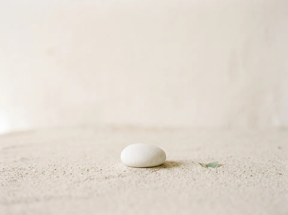 A single smooth white pebble on pale sand.